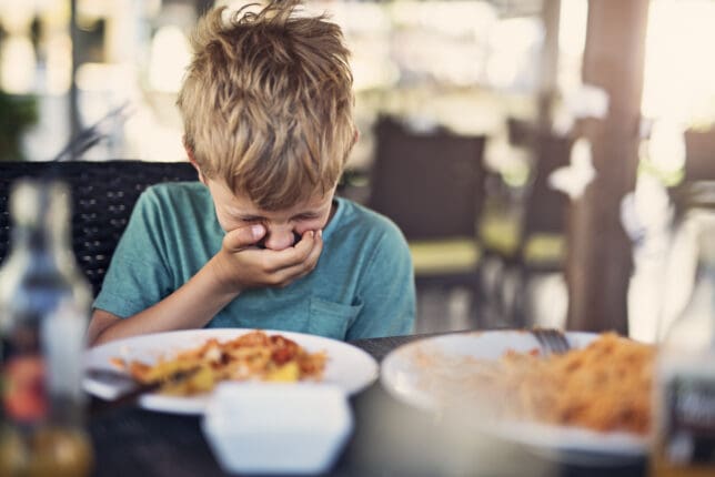 Kleiner Junge angeekelt vom Schulessen, Brechreiz.